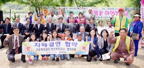 ▲경남밀양시단장면평리녹색농촌체험마을에서열린제6회이팝꽃화합한마당축제에서근로복지공단부산북부지사와평리마을이자매결연을맺고기념촬영을하고있다.