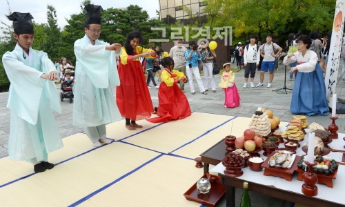 ▲'외국인과함께누리는한가위한마당'에서외국유학생들이차례상앞에서한복을입고절하는체험을하고있다.