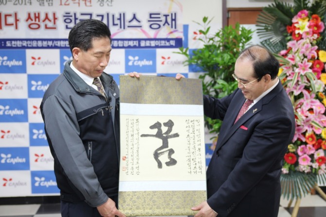 글로벌이코노믹·대한민국최고기록인증원·도전한국인본부는 27일 (주)칸나(대표 이상배) 용인 본사에서 앨범 생산 국내 최다 기록 인증식을 가졌다. 김용진 심사위원장(오른쪽)이 (주)칸나 이상배 대표에게 인증서를 준 뒤 족자를 선물하고 있다.<br />
<br />
