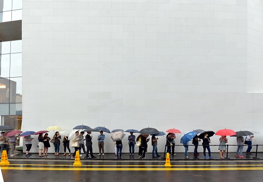 사진은 26일 오전 서울 분더샵 청담에서 스마트워치 '애플워치'를 사려는 사람들이 빗속에서 우산을 쓰고 대기하는 모습