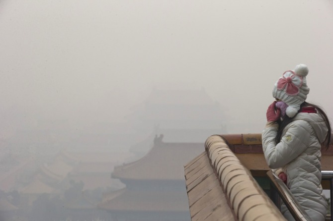 지난 22일(현지시간) 미세 먼지의 대기 오염으로 스모그가 잔뜩 낀 중국 수도에서 한 여성이 마스크를 만지고 있다. 중국에서는 미세먼지와 관련된 새로운 비즈니스가 속속 창출할 전망이다. / 사진 = 뉴시스