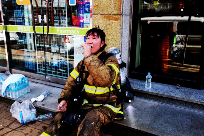 화재현장을 진압한 소방관이 음료수를 마시고 있다.