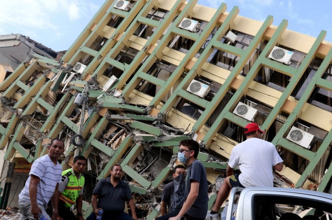 에콰도르 정부 발표에 따르면 16일 발생한 지진으로 인한 피해 규모는 3일이 지난 19일 현재 사망자는 507명, 실종자 수는 4027명으로 각각 집계됐다. 사진은 에콰도르 포르토비에호에 있는 한 건물이 강진으로 인해 옆으로 쓰러져 있는 가운데 18일(현지시간) 주민들이 건물 앞을 지나고 있는 모습. / 사진 = 뉴시스