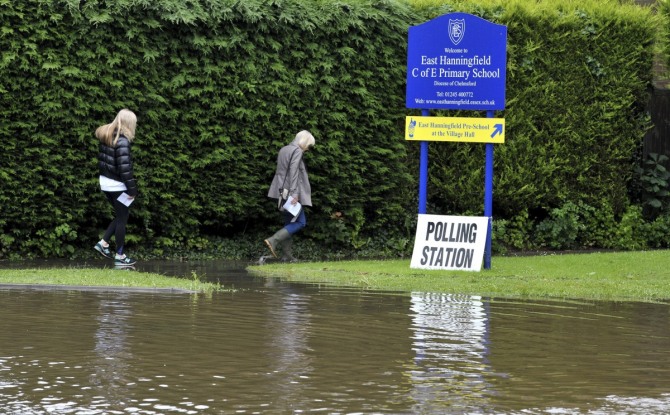 영국 브렉시트 국민투표 날인 23일(현지시간) 오전 이스트 해닝필드에서 젊은이 두 명이 침수된 길가를 따라 걸으며 투표소로 향하고 있다. 이날 런던과 남동부 지방에는 폭우가 쏟아지고 여러 곳에서 홍수가 발생했다. 사진/뉴시스