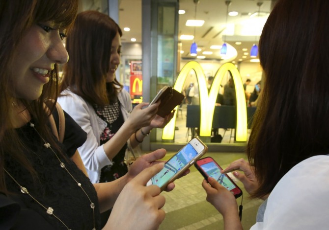 일본 도쿄 맥도날드 매장에서 지난달 22일 여성들이 포켓몬 고 게임을 하고 있다. 일본 맥도날드는 전국 약 2900개 매장 중 400개 매장을 포켓몬 고 게임의 '체육관'으로 지정하고, 약 2500개 매장은 '포케스톱'으로 지정했다. '체육관'은 포켓몬 고 이용자들이 훈련하거나 상대 팀을 상대로 전투를 벌일 수 있는 장소이고, '포케스톱'은 포켓몬을 잡을 수 있는 몬스터볼 등의 아이템을 획득할 수 있는 지역을 말한다. / 뉴시스