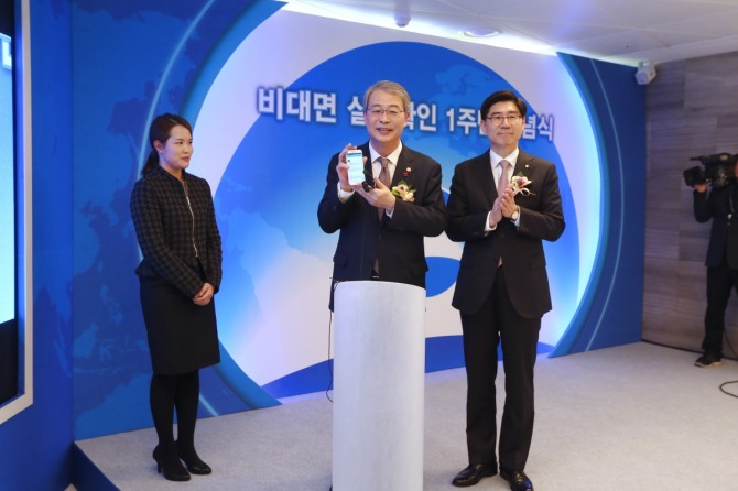 임종룡 금융위원장(사진 가운데)이 비대면 실명확인을 통해 계좌개설 시연을 한 뒤, 이광구 은행장(사진 오른쪽)과 함께 기념촬영을 하고 있다. / 우리은행 