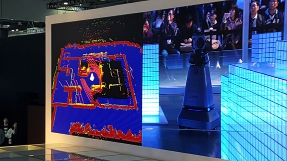 네이버가 실내지도제작 로봇 M1으로 실내 3D지도 제작과정을 시연하는 모습이 스크린에 비쳐지고 있다. 스크린 오른쪽이 M1로봇의 모습. 사진=이재구기자