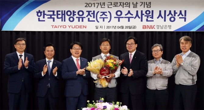 BNK경남은행 손교덕 은행장(왼쪽 세번째)과 한국태양유전㈜ 남필수 대표이사(오른쪽 세번째) 그리고 기업체 우수사원으로 선정된 문성진 과장(가운데)이 기념촬영하고 있다. BNK경남은행=제공 