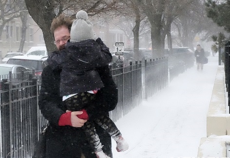 미국 일리노이주 시카고에서 3월 14일(현지시간) 한 남성이 아이를 안고 눈폭풍이 몰아치는 거리를 걸어가고 있다./AP뉴시스
