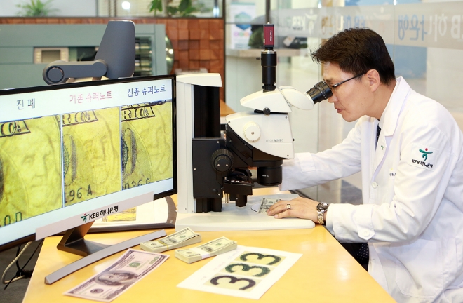 KEB하나은행 위변조대응센터 직원이 전자 현미경을 통해 미국 달러화 지폐의 진폐 여부를 감별하고 있다. 사진=하나은행 제공