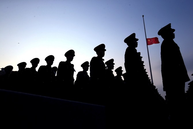 일본군의 난징대학살 80주년 추모식이 열린 중국 난징에서 13일 중국 공안들이 조기가 걸린 오성홍기 아래 도열해 있다. 사진=뉴시스