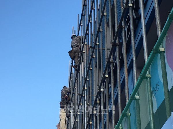 한 건설현장에서 인부들이 안전고리도 없이 얇은 기둥 위에서 고소작업을 벌이고 있다.