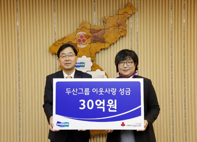 박완석 ㈜두산 부사장(왼쪽)이 김연순 사회복지공동모금회 사무총장에게 성금을 전달하고 기념촬영을 하고 있다. 사진=두산
