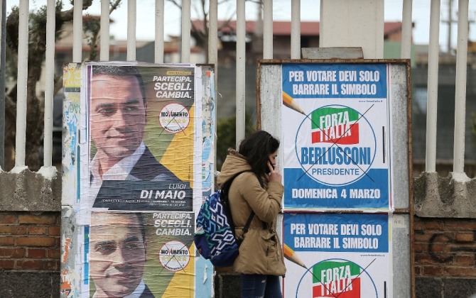 이탈리아 총선을 알리는 포스터가 개시된 가운데 한 시민이 전화를 하며 지나가고 있다. 사진=로이터/뉴스1