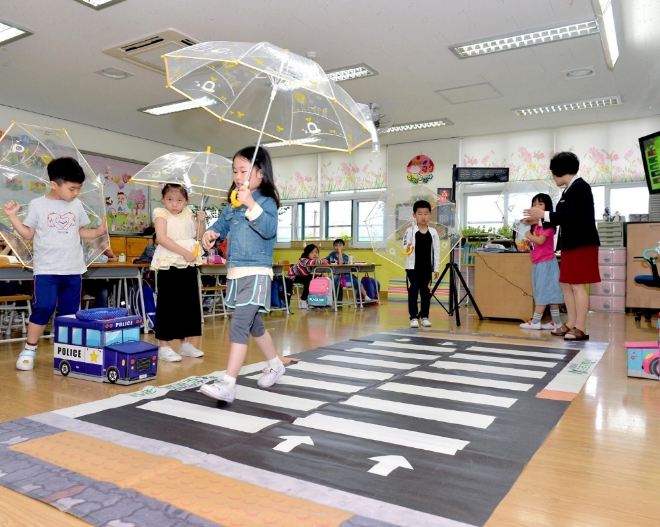 경기도 고양시 아람초등학교 학생들이 투명 우산을 들고 모형 횡단보도를 건너며 교통 안전 교육을 받고 있다. 사진=현대모비스