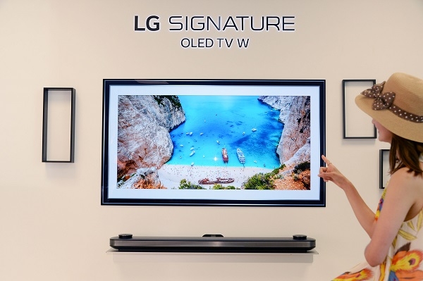 모델들이 LG 시그니처 올레드 TV W의 갤러리 앱에서 트립어드바이저가 추천하는 여름 여행지 사진을 보며 홈캉스를 즐기고 있다. 사진=LG전자.