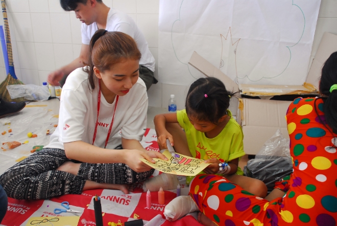 지난달 29일 베트남 푸옌지역의 푸옌병원에서 진행된 ‘베트남 얼굴기형 어린이 무료수술’ 행사에서 다지증(多指症) 수술을 받은 어린이와 SK자원봉사단 SK써니 단원이 놀이수업을 하고 있다. 사진=SK 