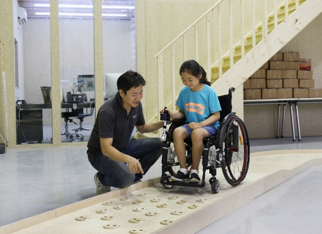 심재신 토도웍스 대표가 토도웍스 사옥에 위치한 휠체어 전용 교육장에서 장애 아동에게 수동휠체어용 전동 키트를 활용한 이동 교육을 진행하고 있다. 사진= 행복얼라이언스