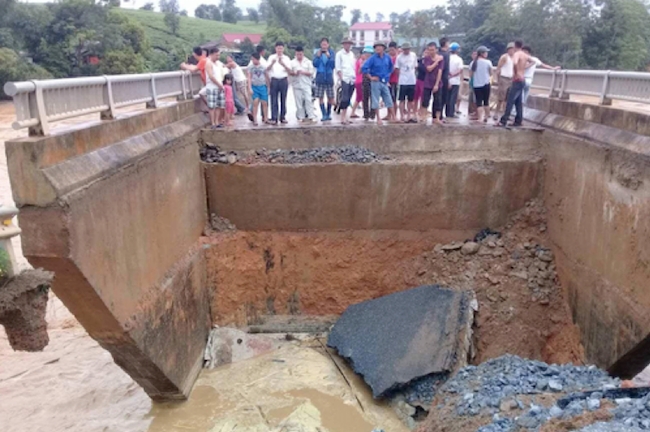 Tan Son구에서 폭우로 인해 끊어진 다리를 주민들이 지켜보고 있다.