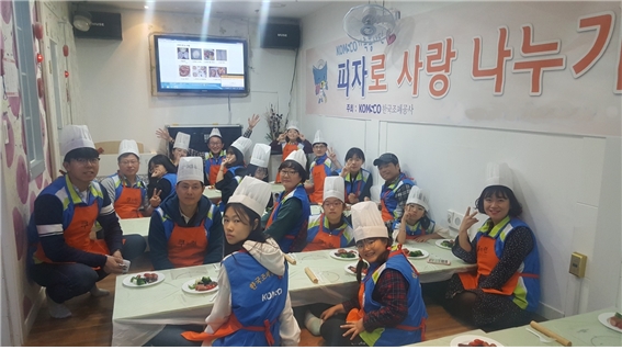 한국조폐공사 임직원들과 봉사단이 지난 21일 대전시 서구 내동에 있는 요리체험교실 쿠키런에서 '피자로 사랑 나누기' 가족봉사단 활동에 참가한 아이들과 함께 기념사진을 찍고 있다. 제공=한국조폐공사