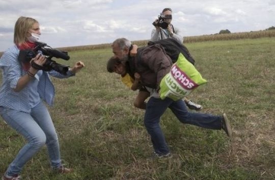헝가리 카메라 여기자 페트라 라슬로(왼쪽)가 아이를 안고 도망치는 난민 남성을 촬영하고 있다.