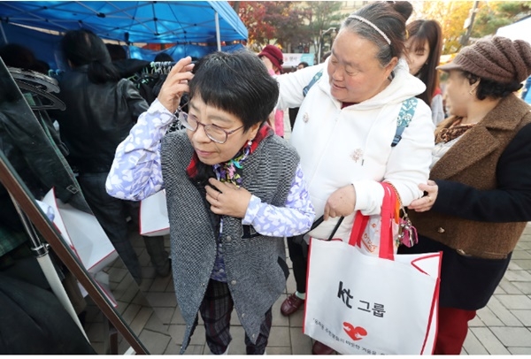 KT 방한복 나눔 행사에 참여한 주민들이 KT 임직원들과 함께 겨울 한파를 대비한 방한복을 고르고 있다. (사진=KT)