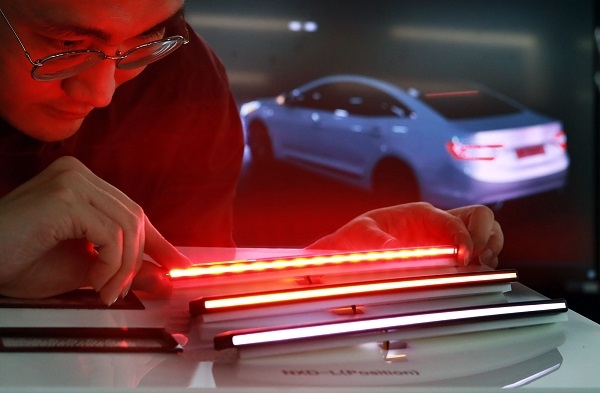 LG이노텍 직원이 차량용 초슬림 라인조명모듈 ‘넥슬라이드-L’을 살펴보고 있다. 사진=LG이노텍.