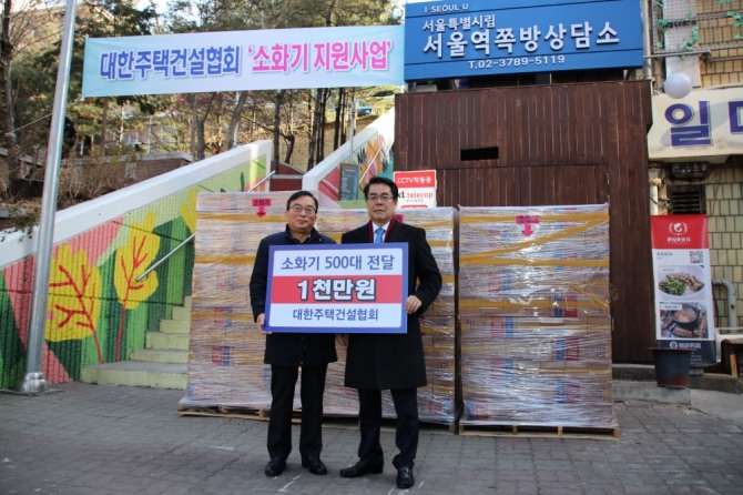 24일 열린 '2019 소방취약계층 소화기 지원행사'에 참여한 심광일 대한주택건설협회 회장(오른쪽)과 서울역 쪽방상담소 관계자(왼쪽)와 기념사진을 찍고 있다. 사진=대한주택건설협회