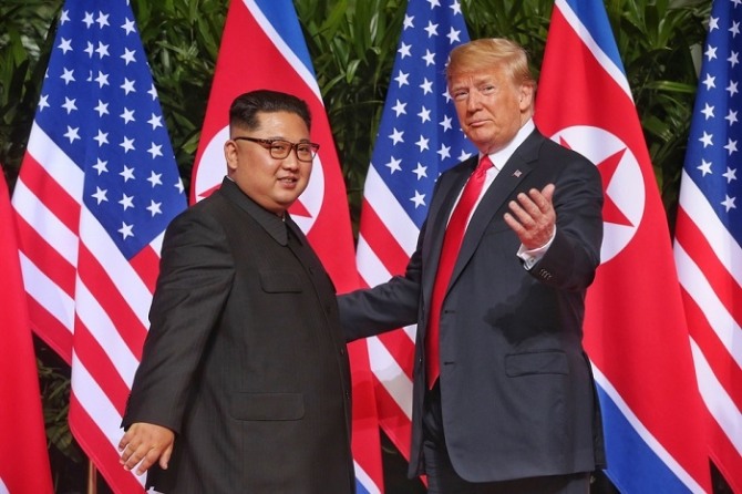 김정은 북한 국무위원장(왼쪽)과 도널드 트럼프 미국 대통령이 지난해 6월 싱가포르 카펠라 호텔에서 만나 악수한 뒤 사진 촬영을 위해 사진기자들을 바라보고 있다.