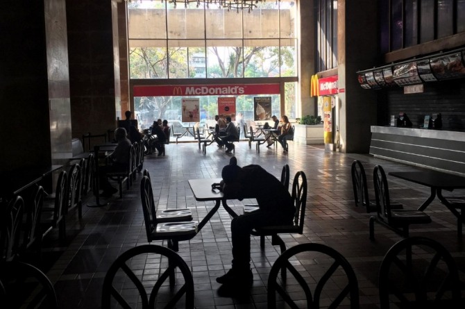 7일 전기가 나간 베네수엘라 카라카스 맥도날드에서 한 고객이 엎드리고 있다. 사진=로이터