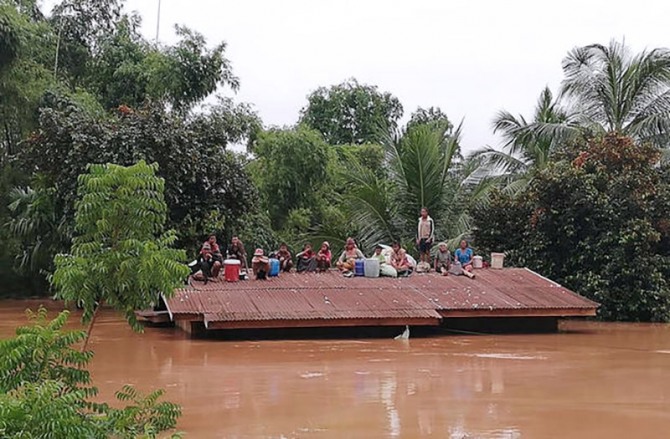 지난해 7월 라오스 남동부 아타프 주에 있는 세피안-세남노이댐의 붕괴로 일어난 갑작스러운 홍수에 대비하지 못해 지붕 위에 위태롭게 피신해 있는 피해 마을 주민들의 모습. 사진=뉴시스