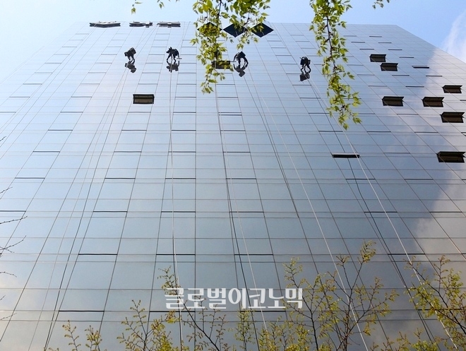 5명의 청소부가 서울 역삼동 아주빌딩 외관을 물청소 하고 있다.
