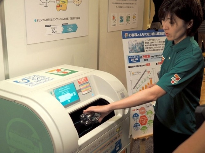 일본 세븐일레븐 종업원이 폐기된 페트병을 모으는 회수기에 페트병을 넣고 있다.  
