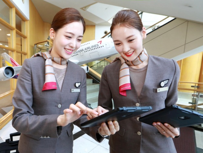 아시아나항공 캐빈승무원들이 새롭게 지급받은 태블릿 PC를 통해 스마트워크 플랫폼 'A-tab'으로 스케줄을 확인하고 있다. 사진=아시아나항공