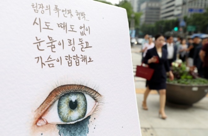서울 종로구 광화문광장 네거리에서 열린 이른바‘갑질금지법’시행 맞이 캠페인장에 설치된 판넬 앞을 시민들이 지나고 있다. 사진=뉴시스