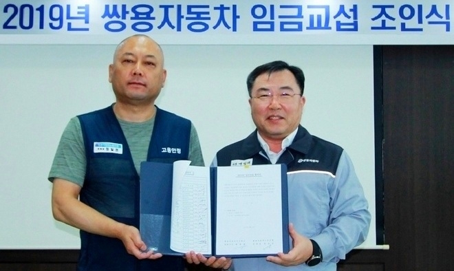 (오른쪽부터)예병태 대표이사와 정일권 노조위원장이 임금협상 합의서에 서명한 후 기념사진을 찍고 있다. 사진=쌍용차