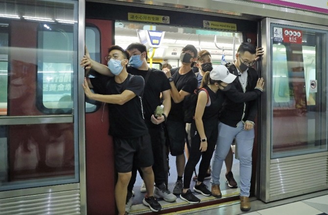지난 21일(현지시간) 홍콩 위엔롱 MTR 역에서 열차에 탑승한 시위대가 열차 출입문을 붙잡고 운행 지연 시위를 벌이고 있다. 사진=AP/뉴시스