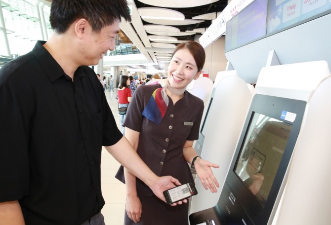 아시아나항공 공항 서비스 직원이 김포공항 국내선 터미널에서 여행객에게 셀프체크인 기기 사용법을 안내하고 있다. 사진=아시아나항공