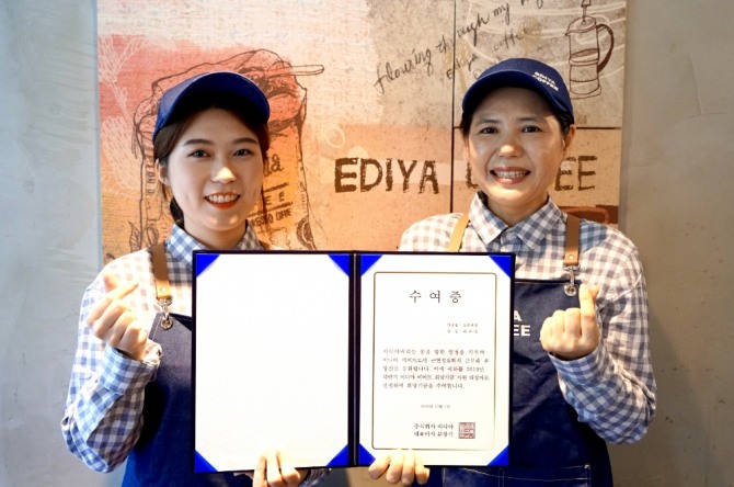 지난 8일 이디야커피 등촌역점에서 이디야 메이트 곽수빈양(사진 왼쪽)이 이디야 메이트 희망기금을 전달받고 점주와 사진 촬영을 하고 있다. 사진=이디야커피