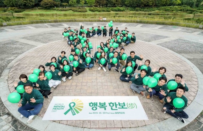한국룬드벡 임직원들이 ‘세계 정신건강의 날’을 기념해 대형 초록 리본을 만드는 세리머니를 펼치고 있다. 사진=한국룬드벡