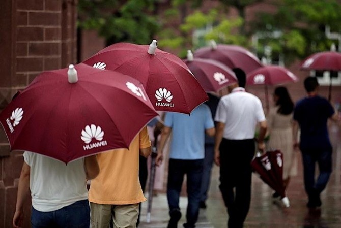 광둥(広東)성 둥관(東莞)시에서 화웨이 로고가 새겨진 우산을 쓰고 길을 가고 있는 시민들 모습. 사진=로이터/뉴스1 
