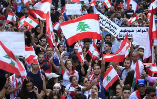 레바논 베이루트에서 21일(현지시간) 시민이 국기를 흔들면서 반정부 시위를 벌이고 있다. 