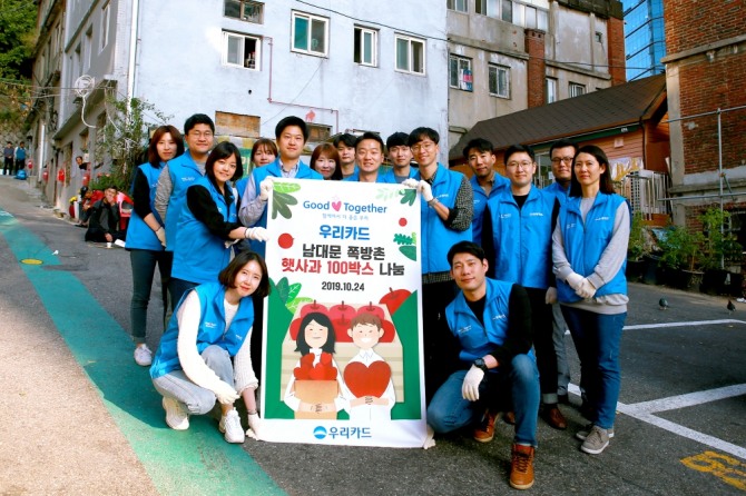 우리카드가 지난 24일 서울 중구의 남대문쪽방촌에서 햇사과를 전달하는 행사를 개최하고 기념촬영을 하고 있다.  사진=우리카드 