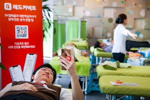 SKT 직원이 레드커넥트 헌혈 캠페인에 참여해 헌혈을 하고 레드커넥트 앱을 사용해보고 있다. 사진=SKT
