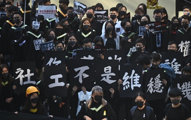 홍콩 반정부시위 이후 첫 사망자가 나온 가운데 현지시간 7일 홍콩중문대학교에서 열린 졸업식에 참석한 졸업생들이 가면이나 마스크를 쓴 채 플래카드를 들고 반정부구호를 외치고 있다.