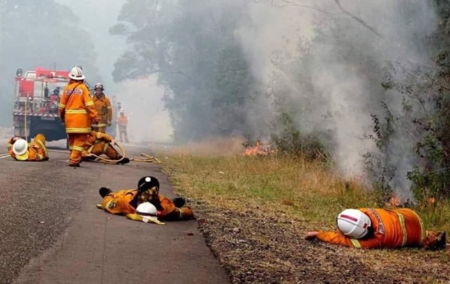 호주 동부지역에 발생한 초대형 산불로 비상사태가 선포된 가운데 10일(현지시간) 화재를 진화하기 위해 사력을 다해 탈진한 소방관들이 불길이 남아있는 도로에 쓰러져 쉬고 있다.