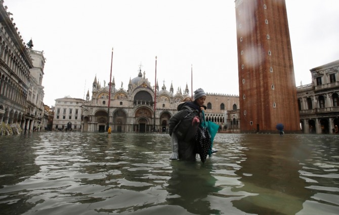 이탈리아 베네치아에서 12일(현지시간) 53년래 최악의 홍수가 발생해 산마르코 광장이 바닷물에 잠겨 있는 가운데 한 여성이 아이를 업고 물을 헤치며 걷고 있다. 사진=뉴시스