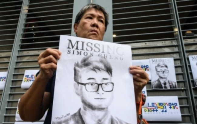 한 홍콩시민이 전 홍콩주재 영국 영사관 직원인 사이먼 첸의 포스터를 들고 있다.