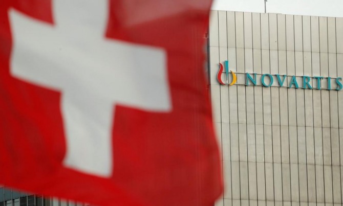 스위스 바젤의 제약회사 노바티스 로고 앞에 스위스 국기가 펄럭이고 있다. 사진=로이터통신
