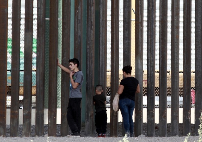 멕시코쪽에서 바라본 미 텍사스주 엘패소의 국경장벽. 세 명의 이민자들이  미국 쪽을 건너다 보고 있다.  남부 텍사스 지역에서는 이 같은 장벽의 건설공사가 최근 가속화되었다.사진=뉴시스